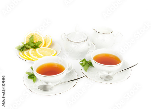 Two cups with tea, teapot, milk and lemon