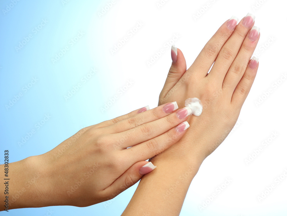 Beautiful woman hands with cream, on blue background Beautiful woman hands with cream, on blue background