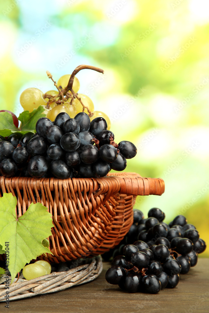 assortment of ripe sweet grapes in basket, on green background assortment of ripe sweet grapes in basket, on green background