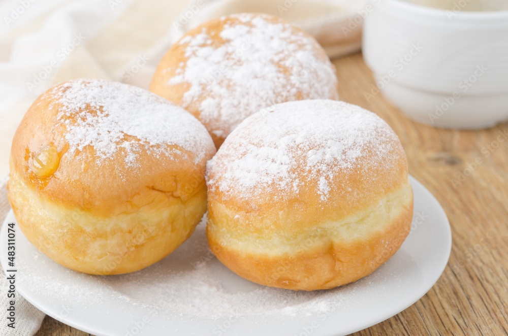 three sweet donuts sprinkled with powdered sugar
