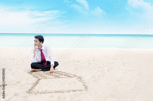 Businessman thinking on a beach © Creativa Images