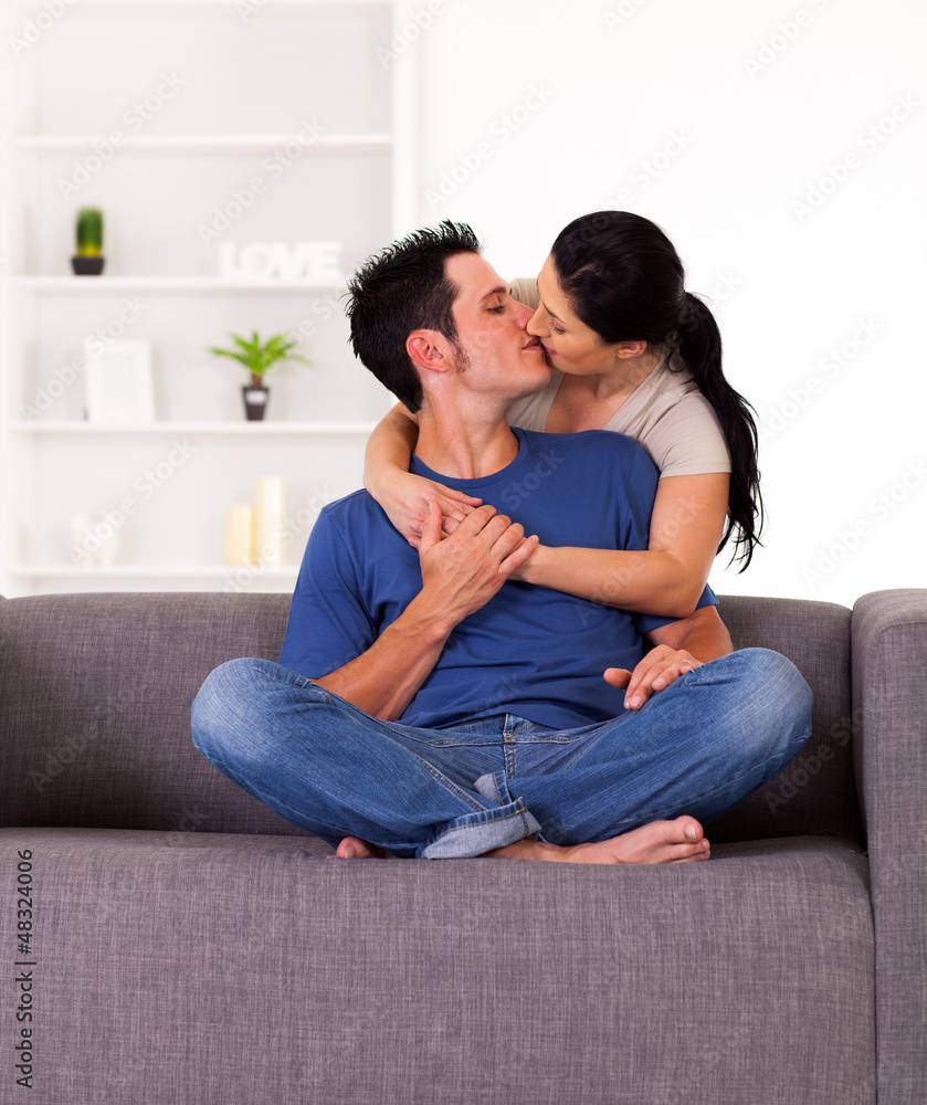 young couple kissing on sofa at home