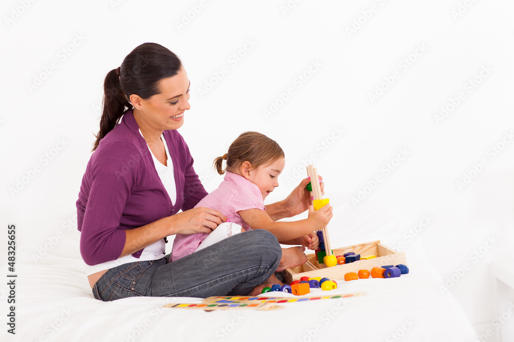 little girl playing educational toy with mother on bed little girl playing educational toy with mother on bed
