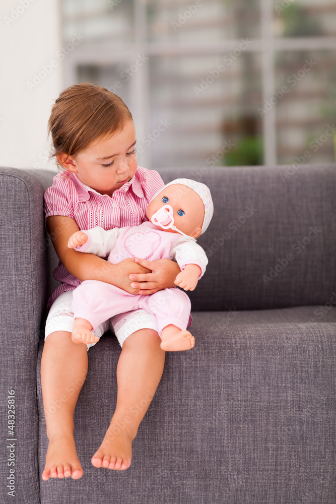 cute little girl playing with doll at home Stock Photo | Adobe Stock