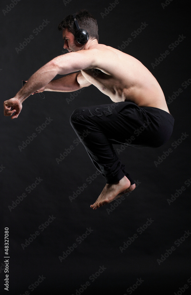Young man jumping and listening music isolated gray background