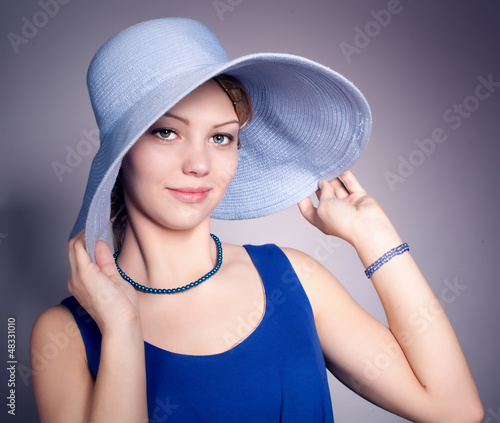 young woman wearing darkblue dress and blue big hat