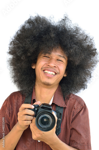 Smiling young man with long hair and holding digital camera © singkham