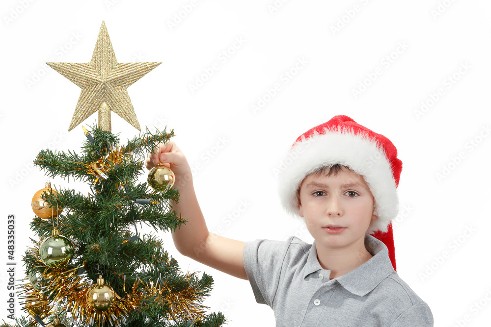 Boy with santa hat decorates the Christmas tree Boy with santa hat decorates the Christmas tree