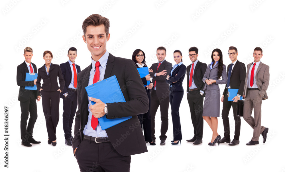 Leader holding a clipboard with business team behind Leader holding a clipboard with business team behind
