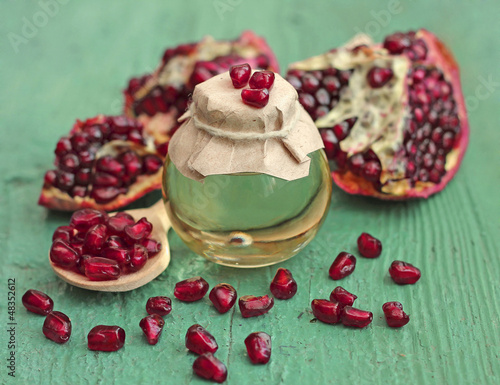 Pomegranate seed oil in bottle on blue wooden background, close-