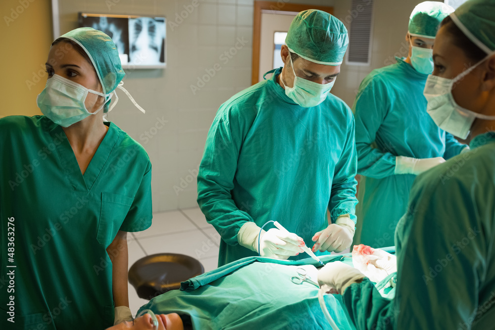 Team of surgeons working on the stomach of a patient Team of surgeons working on the stomach of a patient