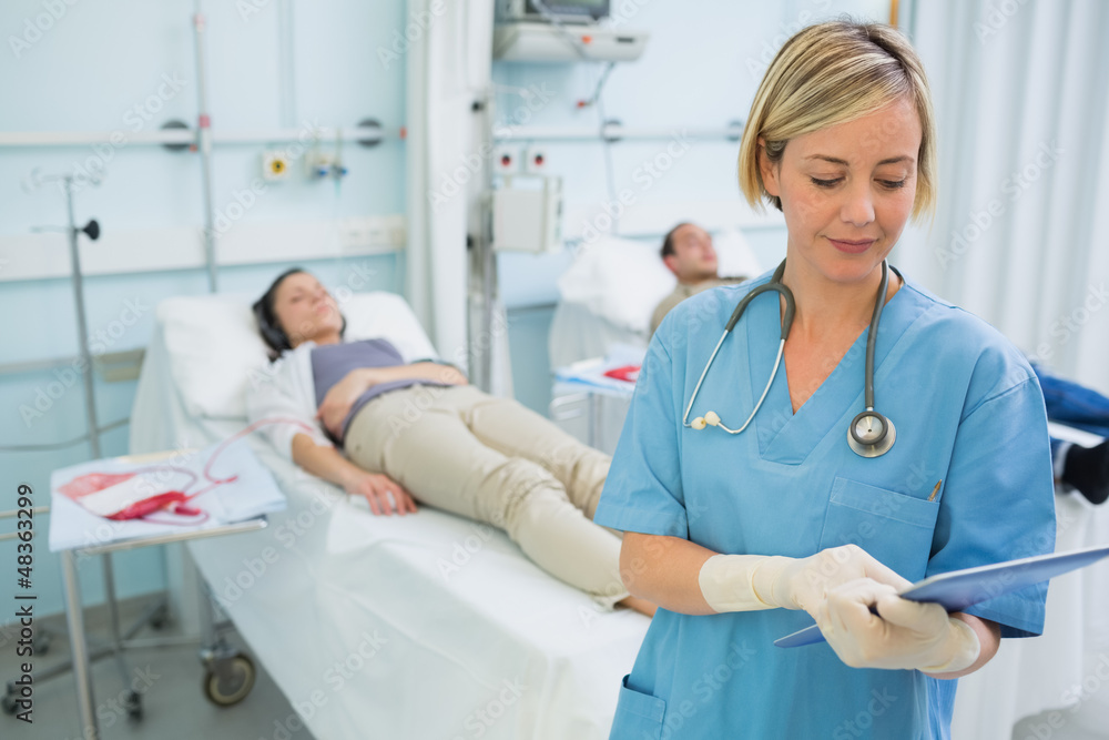 Nurse standing while looking at a clipboard Nurse standing while looking at a clipboard