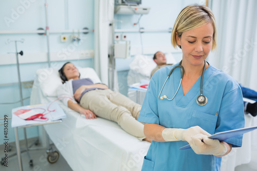 Nurse standing while looking at a clipboard