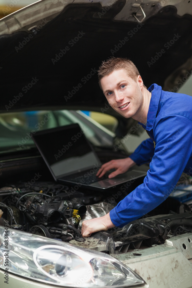 Car mechanic with laptop checking engine Car mechanic with laptop checking engine