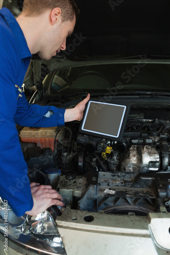 Mechanic by car holding tablet pc