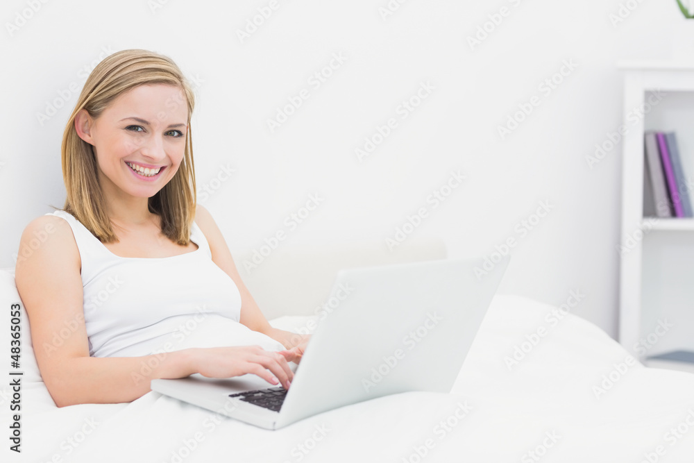 Portrait of happy woman using laptop in bed Portrait of happy woman using laptop in bed
