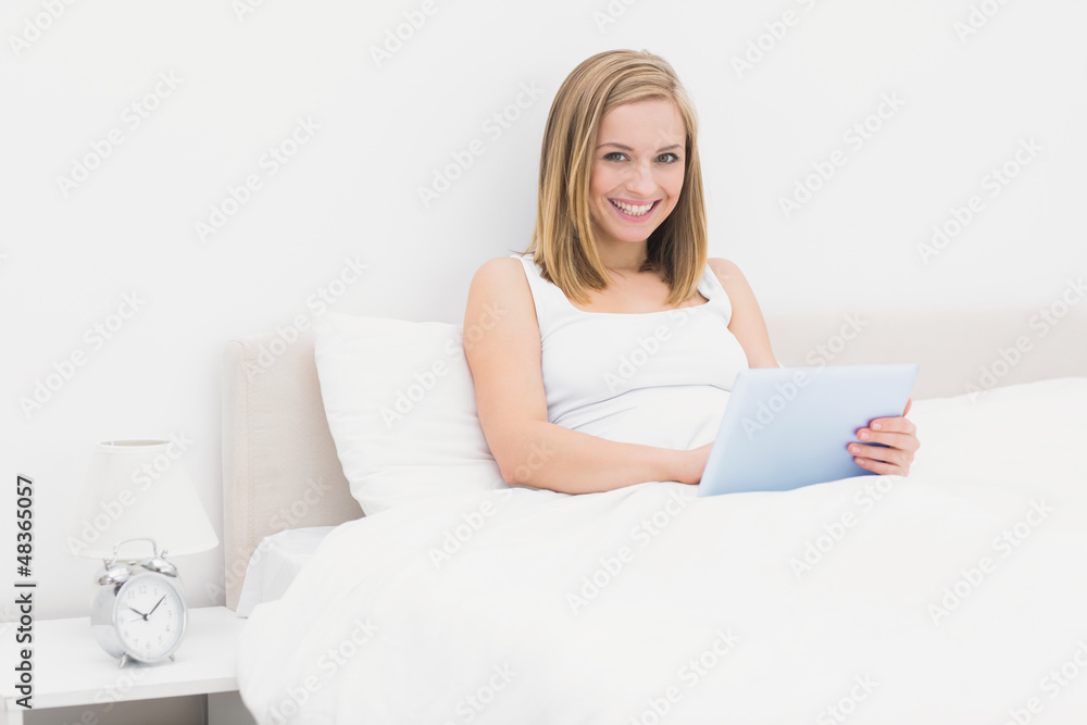 Portrait of smiling woman using digital tablet in bed Portrait of smiling woman using digital tablet in bed