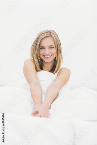 Portrait of smiling woman sitting in bed