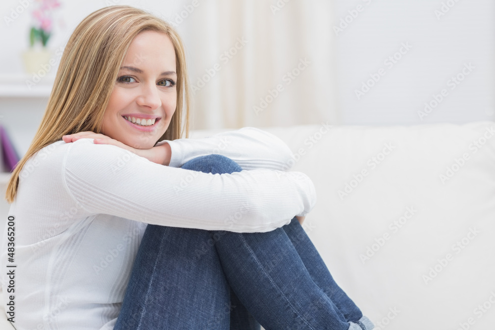 Naklejka premium Portrait of casual happy woman sitting on sofa