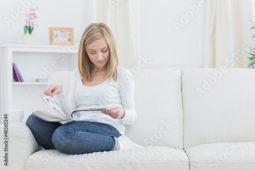 Casual young woman reading magazine at home