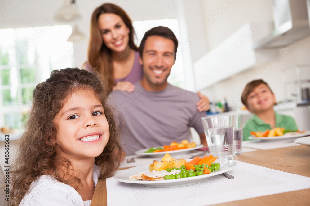 Family smiling at the camera at dinner table