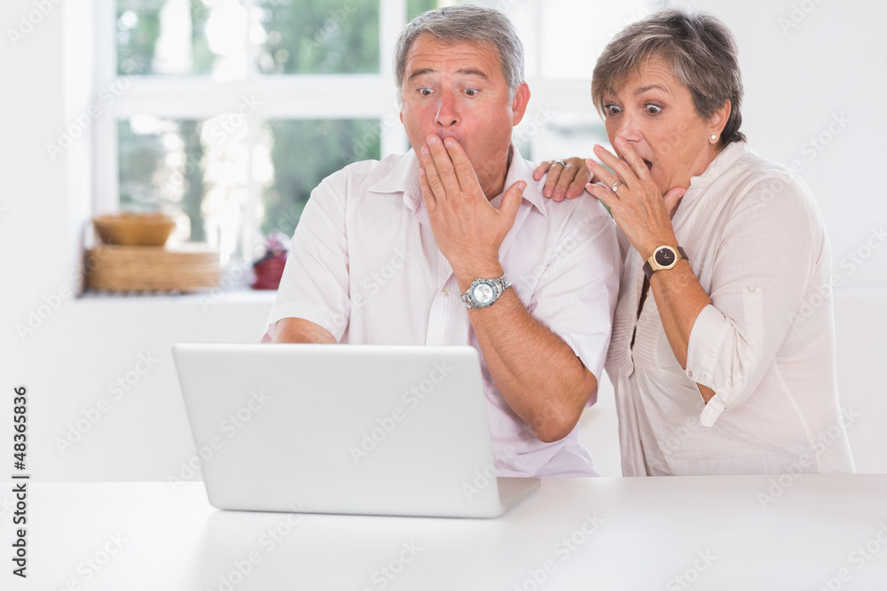 Old couple surprised in front of a laptop Old couple surprised in front of a laptop
