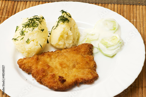 potatoes, pork chop and salad with cucumbers and cream