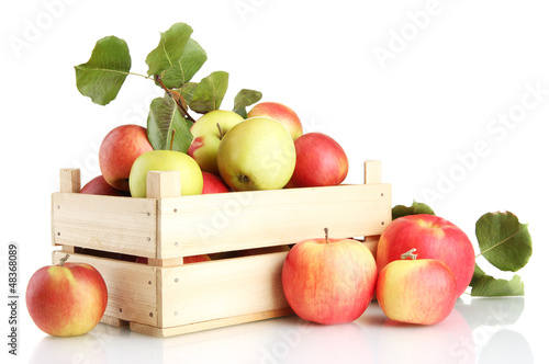 juicy apples with green leaves in wooden crate, isolated