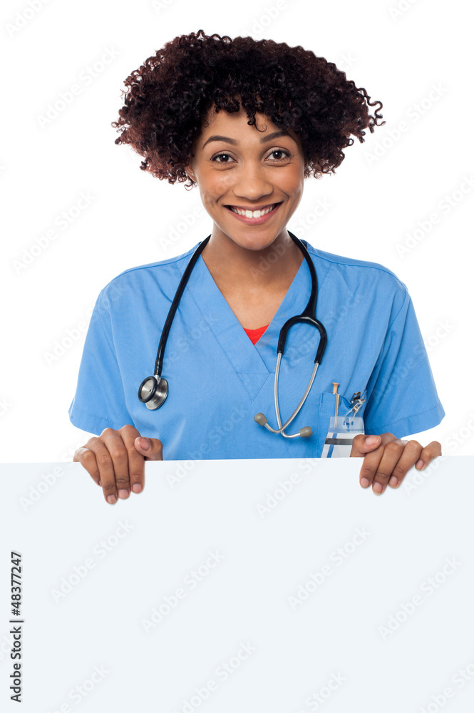 Joyous female doctor standing behind ad board Joyous female doctor standing behind ad board