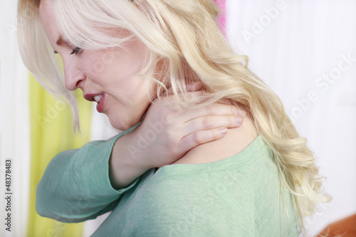 Hübsche blonde Frau mit Nackenschmerzen