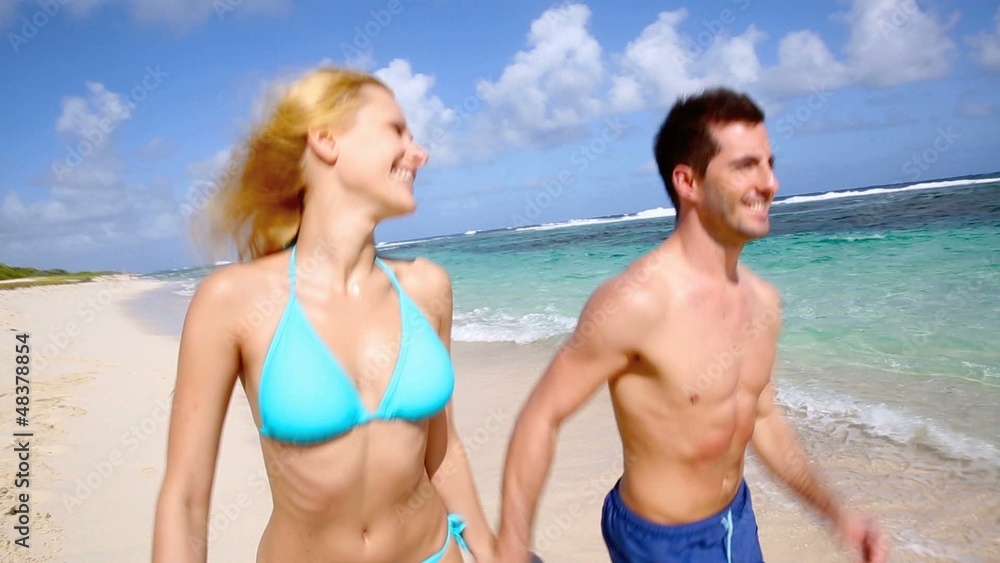 Couple running on sandy beach in caribbean island Couple running on sandy beach in caribbean island
