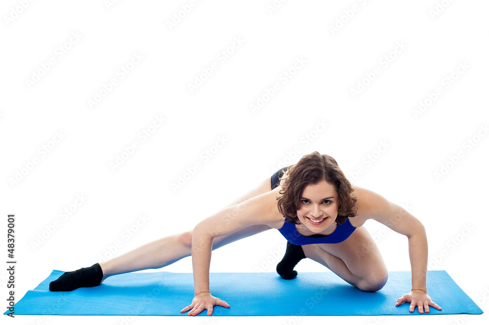 Fit woman crouching on blue mat, studio shot