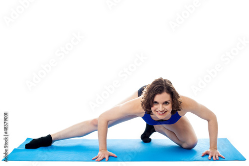 Fit woman crouching on blue mat, studio shot