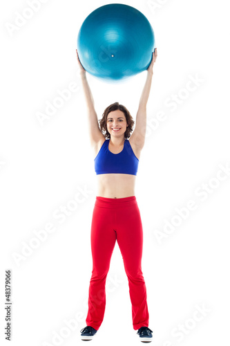 Happy woman lifting pilates ball upwards © stockyimages
