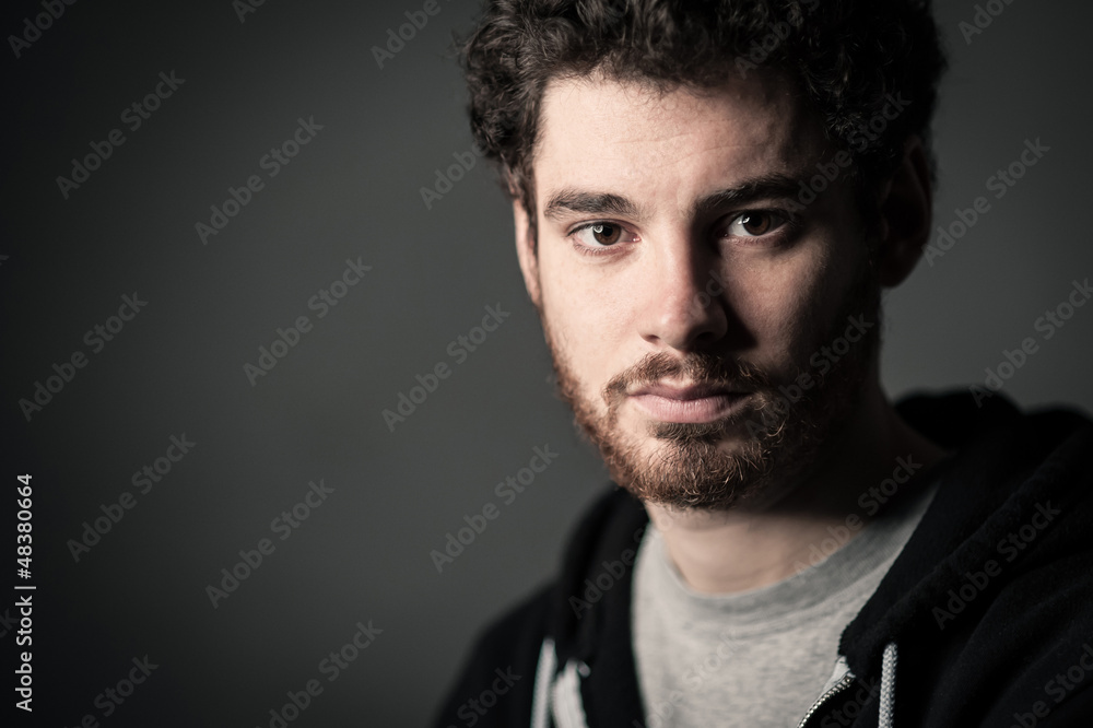 Young man close up portrait against dark background.