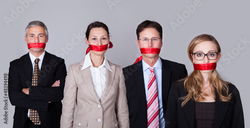 Businesspeople bound by red tape photo