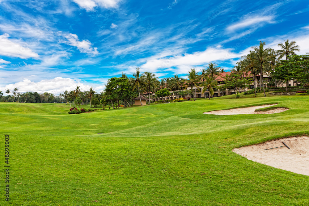 Golf course with palm trees over blue cloudy sky