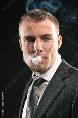 Fashion man in suit smoking cigarette. Studio shot.