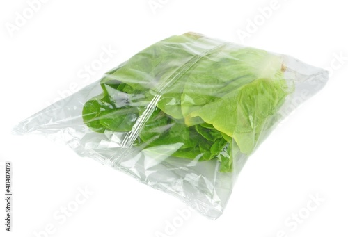 A sealed plastic bag of lettuce on a white background
