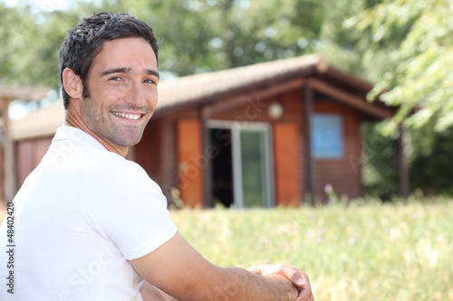Smiling man sitting in front of a cabin photo
