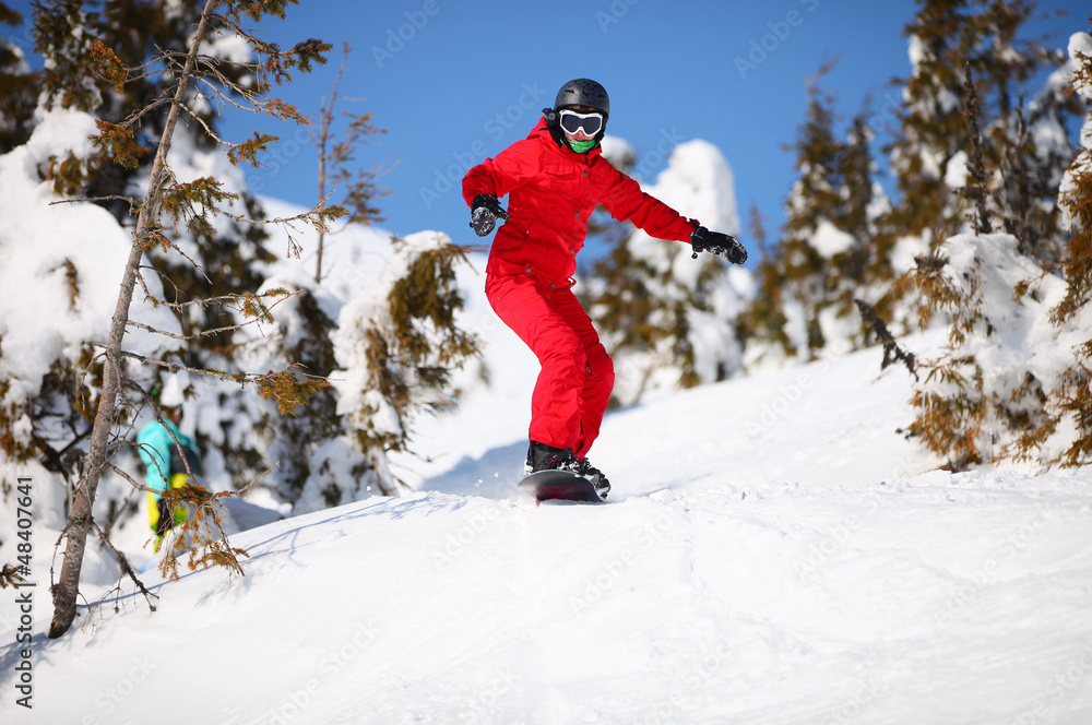 Female snowboarder going to jump on mountain slope