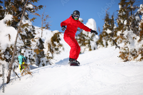 Female snowboarder going to jump on mountain slope