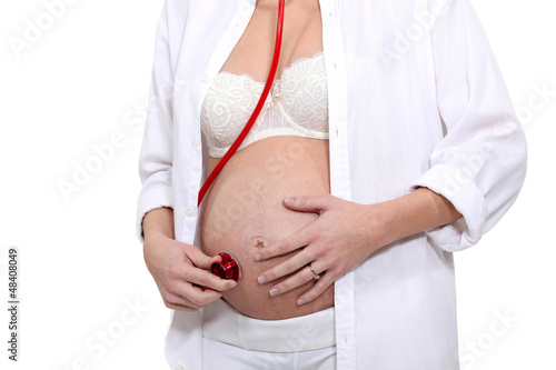 pregnant woman listening her baby with a stethoscope