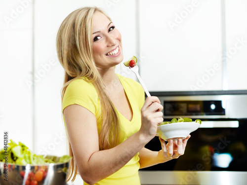 Pretty girl in the kitchen eating healthy food to lose weight photo