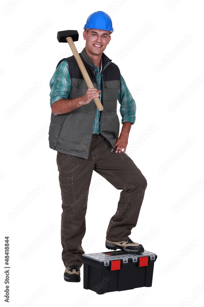 Man with sledge-hammer resting foot on tool-box Man with sledge-hammer resting foot on tool-box