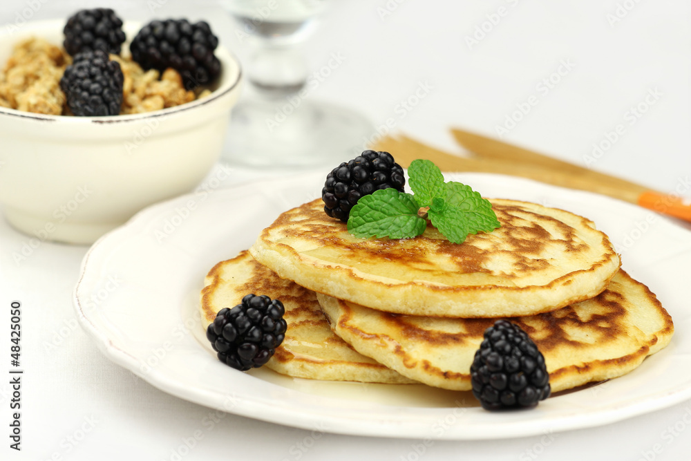 Fluffy pancakes topped with honey, blackberries and fresh mint Fluffy pancakes topped with honey, blackberries and fresh mint