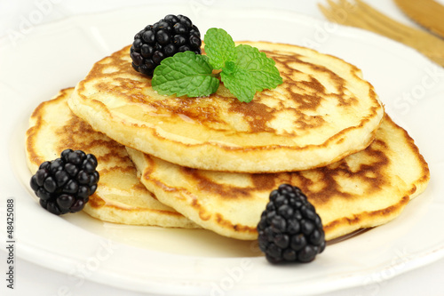 Fluffy pancakes topped with honey, blackberries and fresh mint
