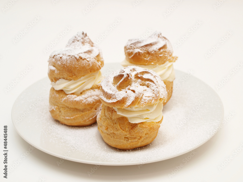 Choux pastry buns, filled with whipped cream, on a plate