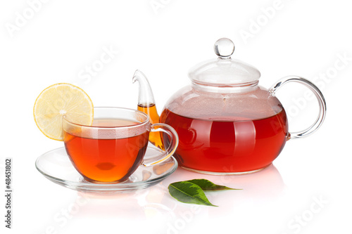 Glass teapot and cup of black tea with lemon slice