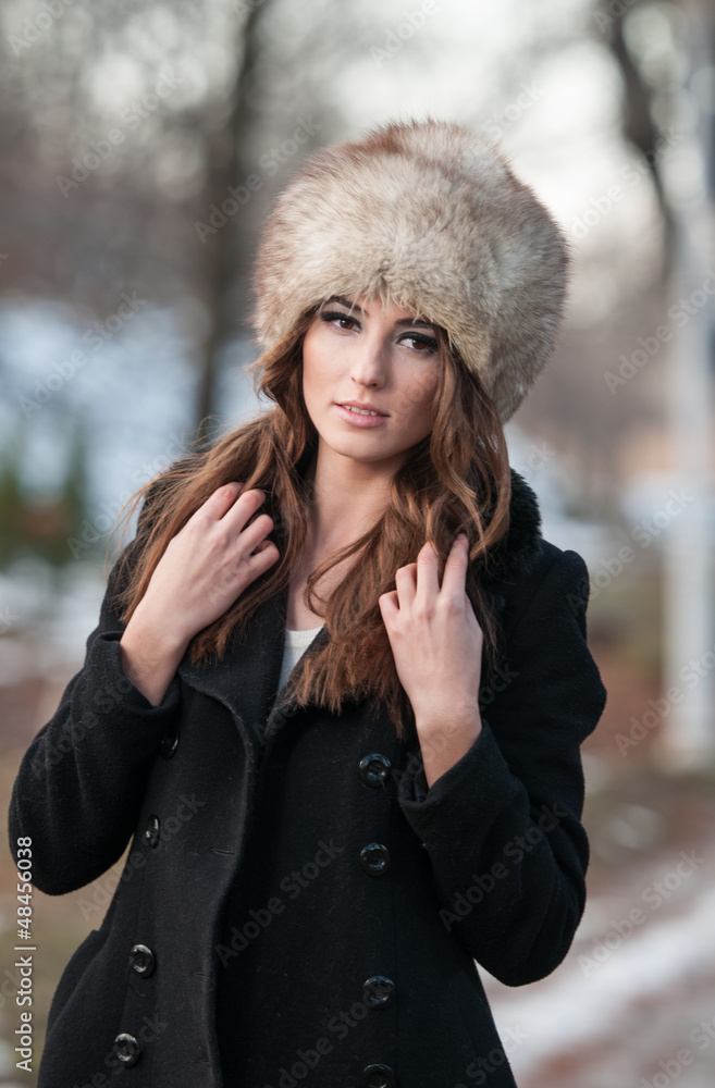 young woman wearing coat walking down the street, cold winter